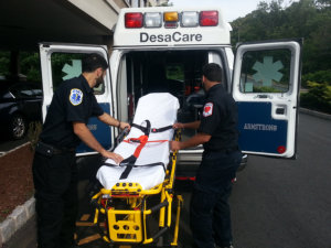 two men pushing a medical stretcher inside a medical transportation